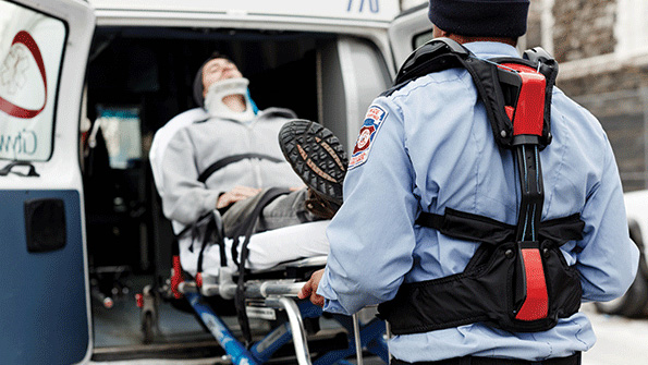 A paramedic uses the help from Strong Arm technologies V22 passive exoskeleton vest to reduce injuries while lifting a patient into the ambulance
