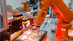 An ABB robotic arm assembles small components in a factory setting.