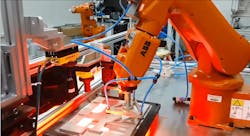 An ABB robotic arm assembles small components in a factory setting An ABB robotic arm assembles small components in a factory setting