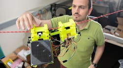 Graduate Research Assistant Gennaro Notomista shows the components of SlothBot on a cable in a Georgia Tech lab. The robot is designed to be slow and energy efficient for applications such as environmental monitoring.