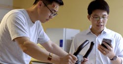 Researcher Wei Gao (right) monitors data from two flexible sweat sensors worn by a volunteer on his wrist and forehead.