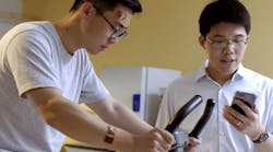 Researcher Wei Gao (right) monitors data from two flexible sweat sensors worn by a volunteer on his wrist and forehead.