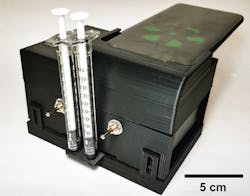 The microfluidic cartridge can be inserted into a portable device that also has a cradle for a smartphone, so the phone’s camera can read the test results. The microfluidic cartridge can be inserted into a portable device that also has a cradle for a smartphone, so the phone’s camera can read the test results.
