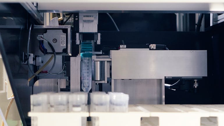 The Festo EXCM mini-gantry robot&rsquo;s gripper (background) is about to lower itself and grip the cap as the test tube is rotated. The small footprint of the gantry made it well suited for ensuring the overall machine was compact for lab use.