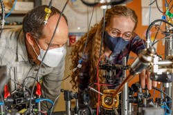 Peter Schwindt, a Sandia National Laboratories scientist (left), and postdoctoral scientist Bethany Little examine the vacuum package held in a yellow, 3D-printed mount.