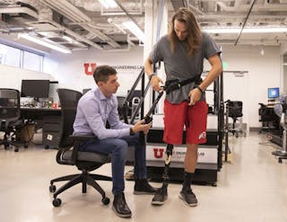 Tommaso Lenzi (left), a University of Utah mechanical engineering assistant professor, helps Alec McMorris put on an experimental exoskeleton. Lenzi developed the medical device for lower-limb amputees. The lightweight powered exoskeleton allows users to walk with much less effort thanks to a series of motors, microprocessors and advanced algorithms.