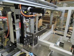 This cantilevered Y and Z axes system, center, pushes product into the wraparound case at the end of the slot. This cantilevered Y and Z axes system, center, pushes product into the wraparound case at the end of the slot.