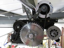 For improved control, the OEM motor (shown above at bottom right) was replaced by an AutomationDirect IronHorse motor (top right), and a bicycle sprocket was installed in conjunction with an AutomationDirect AHS Series extended range inductive proximity sensor to act as a pulse-counting position indicator. For improved control, the OEM motor (shown above at bottom right) was replaced by an AutomationDirect IronHorse motor (top right), and a bicycle sprocket was installed in conjunction with an AutomationDirect AHS Series extended range inductive proximity sensor to act as a pulse-counting position indicator.