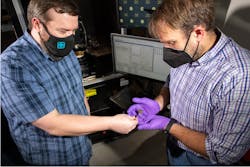 Luke Yates (left), a Sandia National Laboratories electrical engineer, passes Jack Flicker, a grid resiliency expert, a gallium nitride wafer with an array of diodes that can shunt a record-breaking 6,400 volts of electricity within a few billionths of a second. Luke Yates (left), a Sandia National Laboratories electrical engineer, passes Jack Flicker, a grid resiliency expert, a gallium nitride wafer with an array of diodes that can shunt a record-breaking 6,400 volts of electricity within a few billionths of a second.