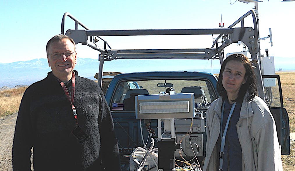 A prototype LightSlinger antenna is flanked by Los Alamos researchers John Singleton and Andrea Schmidt at Los Alamos airport where it was tested and successfully transmitted high-fidelity music.