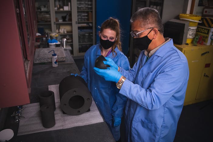 Laboratory scientists Chris Chen and Brianna Musico inspect a certifiable test object developed through the P-HIP process.