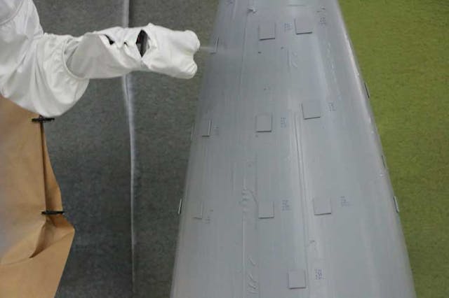 An Aerobotix robotic painting system sprays a topcoat onto an aircraft panel.