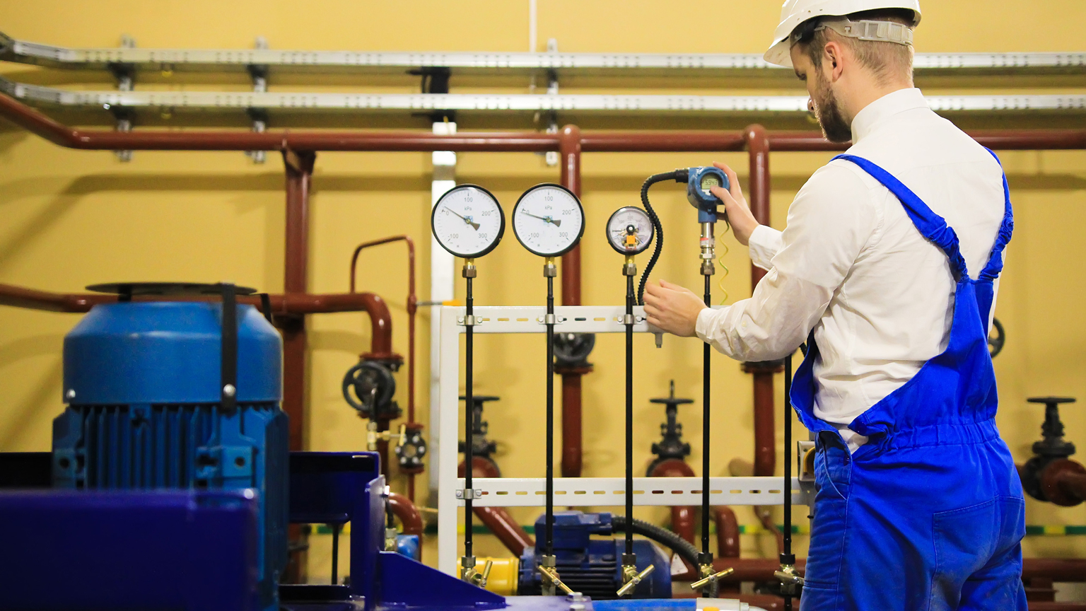 Engineer adjusts pressure sensors on industrial refinery plant