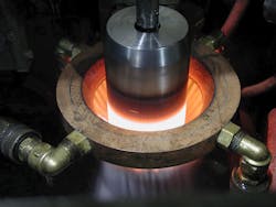 This shaft is undergoing induction hardening. Localized heating on the shaft (red/white glow) is immediately followed with a sprayed-water quench that rapidly cools it. This shaft is undergoing induction hardening. Localized heating on the shaft (red/white glow) is immediately followed with a sprayed-water quench that rapidly cools it.
