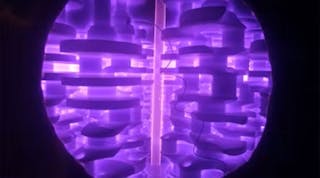 A part being ion nitrided in a vacuum chamber. The purple glow stems from a plasma discharge around the part.