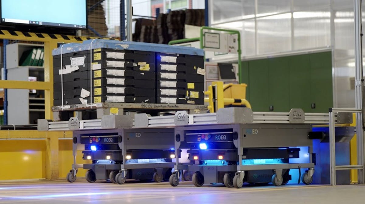 Autonomous mobile robots (AMRs) transport containers with small parts on specially designed carts with racks, towing them via an attached hook.