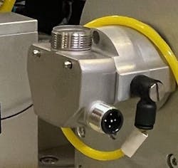 Closeup of the die-cast housing mounted on the rotary drive. The circular cover opening is pointing up, ready to receive adhesive. Closeup of the die-cast housing mounted on the rotary drive. The circular cover opening is pointing up, ready to receive adhesive.