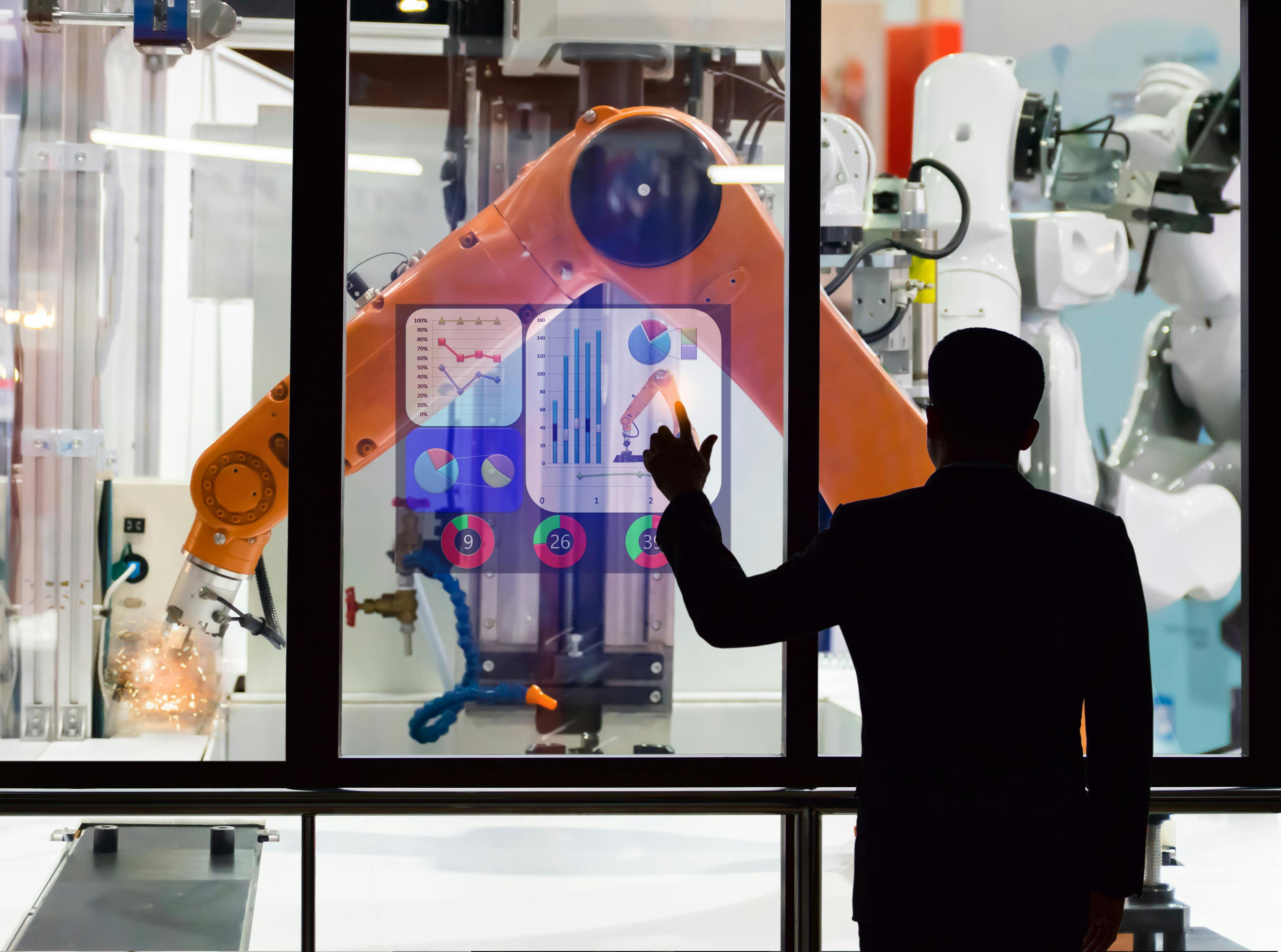 An engineer using a touchscreen to monitor manufacturing robots remotely.