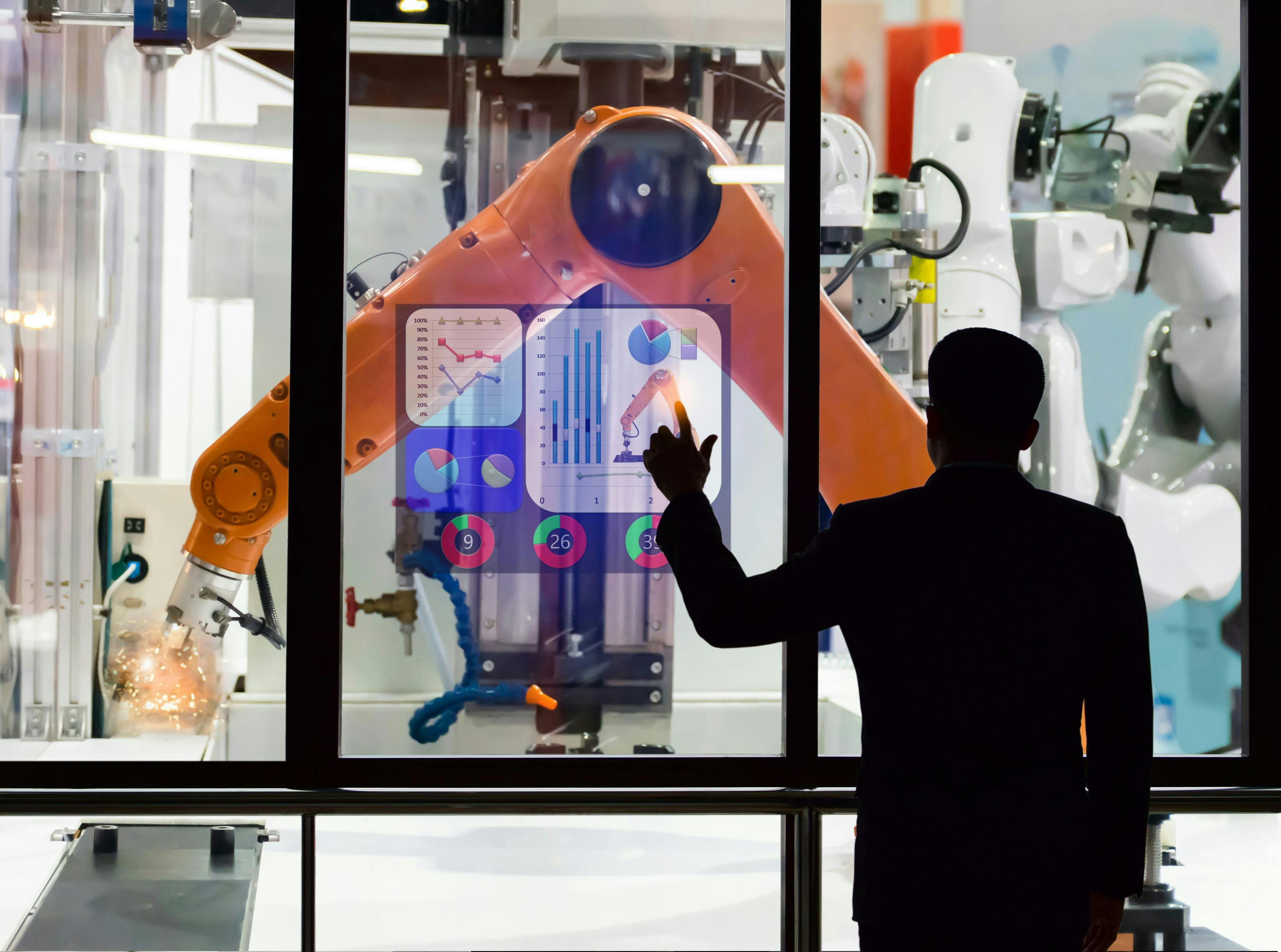 An engineer using a touchscreen to monitor manufacturing robots remotely.