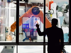 An engineer using a touchscreen to monitor manufacturing robots remotely. An engineer using a touchscreen to monitor manufacturing robots remotely.