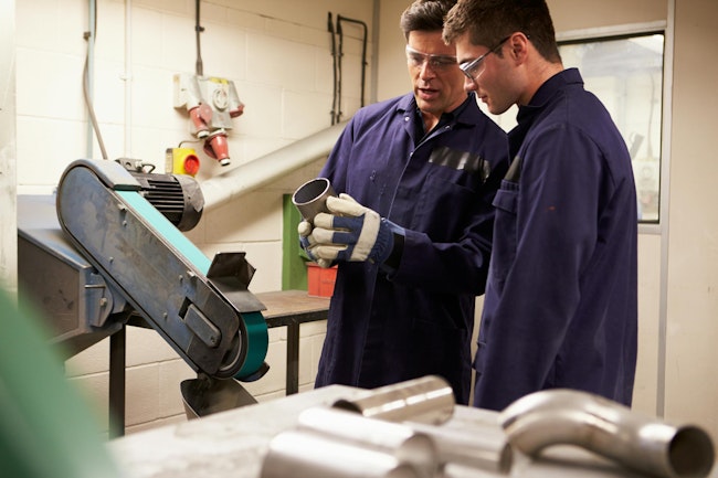 Engineer teaching apprentice to use grinding machine