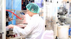 Robotic arm lifting ampoules at packaging line in pharmaceutical factory. Robotic arm lifting ampoules at packaging line in pharmaceutical factory.