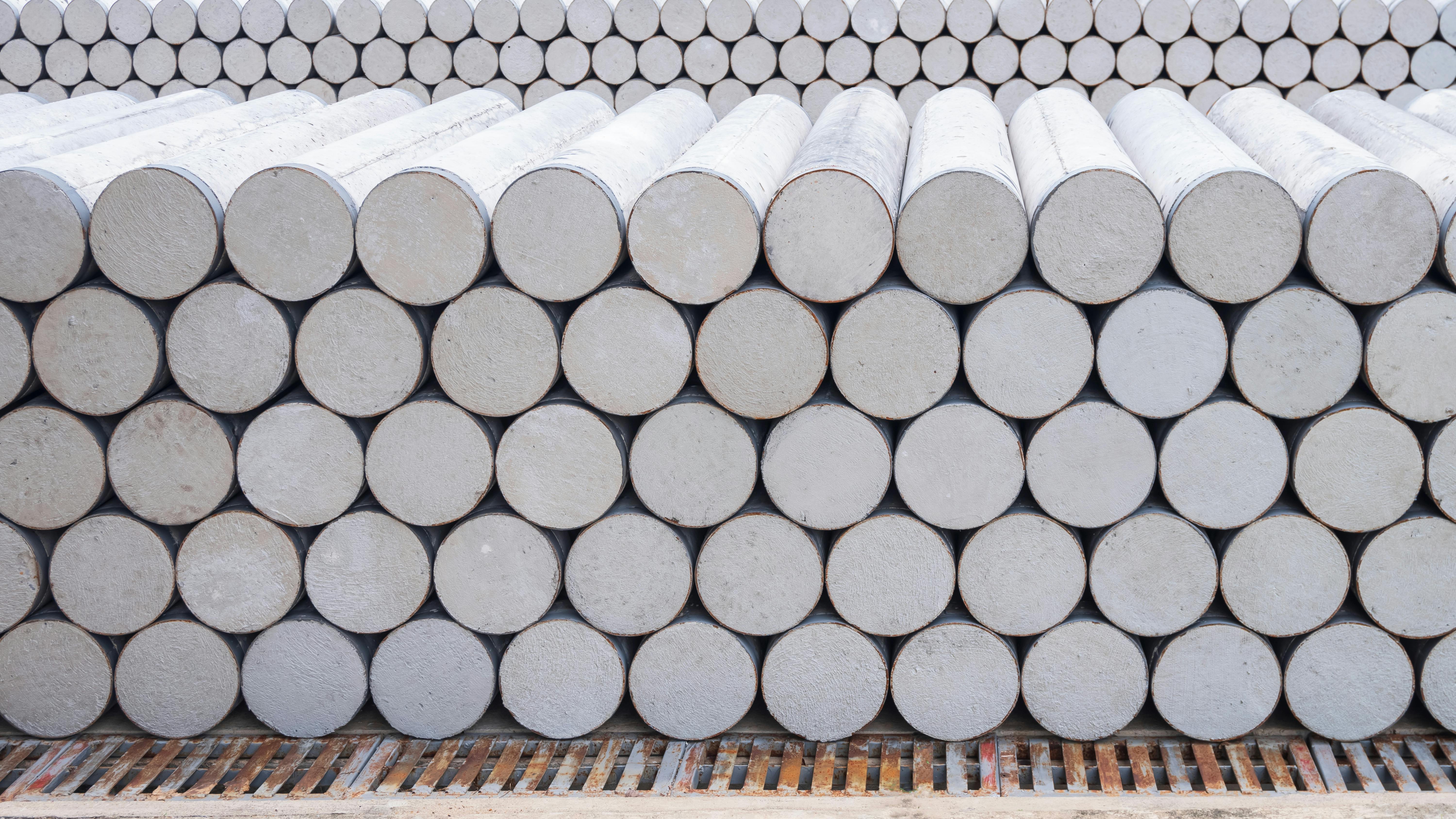 Pile of many precast spun micropiles construction material stacked on the floor in industry yard area for building foundation work. Concrete cylinder micropile background.
